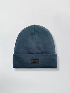 Blue teal Satin Lined beanie with a logo on a light gray background